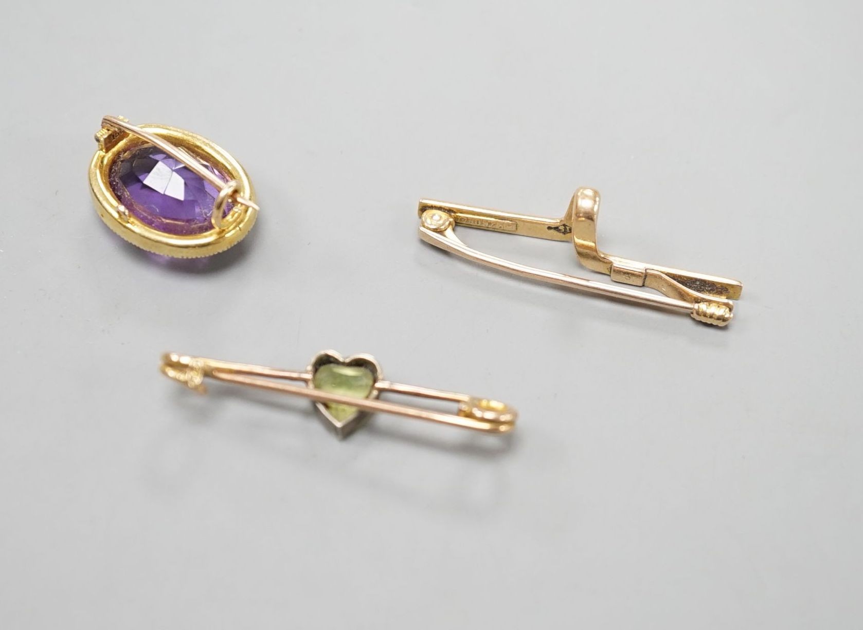 A yellow metal cravat pin, 37mm, a 9ct and heart shaped gem set bar brooch and a yellow metal, amethyst and seed pearl set oval brooch, gross weight 10.4 grams.